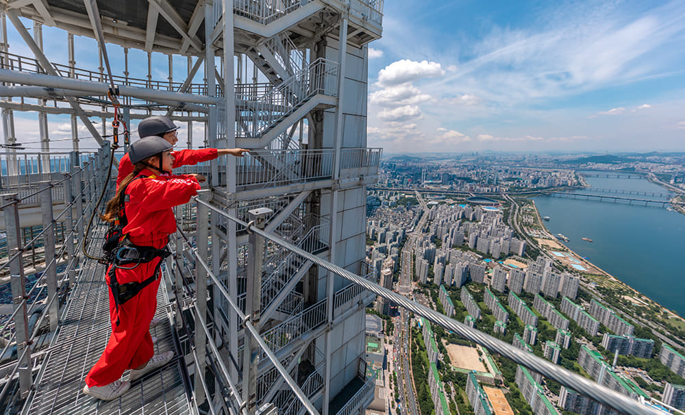 Dua orang sedang berdiri di atas Skybridge Lotte World Tower sambil melihat pemandangan Han River