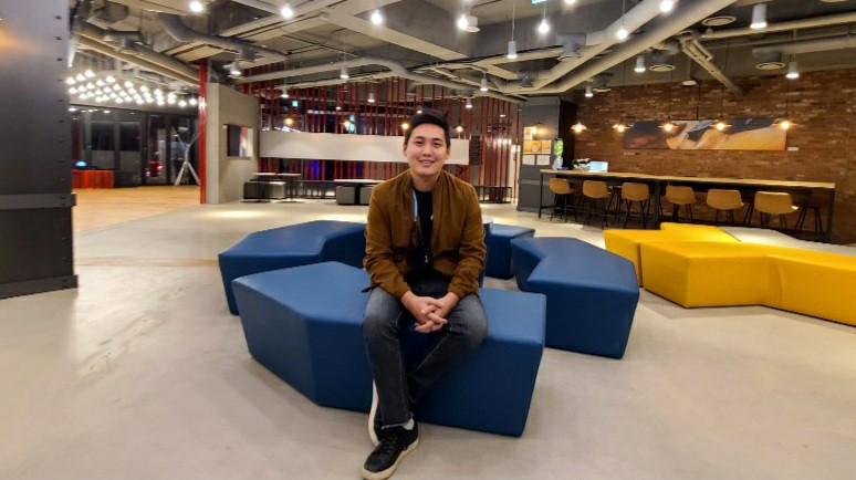 A man is shown sitting in a blue chair.