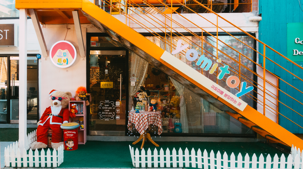 Yomitoy store letting on a staircase at an angle with the store front window and entrance underneath the staircase with a hanging open sign