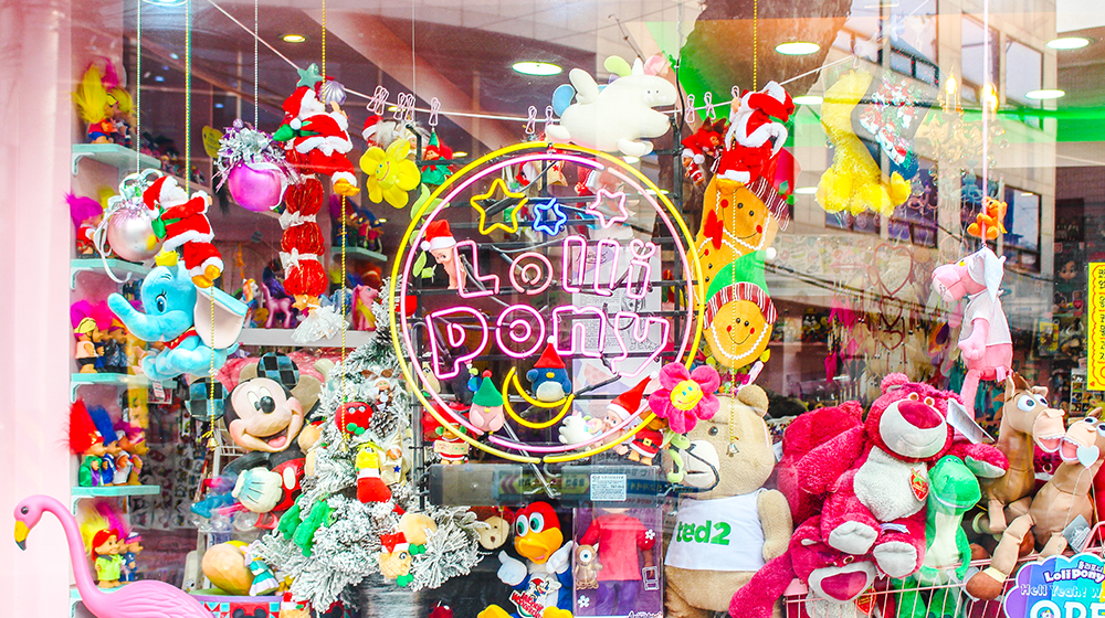 Lolli Pony store front and all sorts of dolls on display behind the window, including Mickey Mouse, Ted, Dumbo, Woody Woodpecker, and more