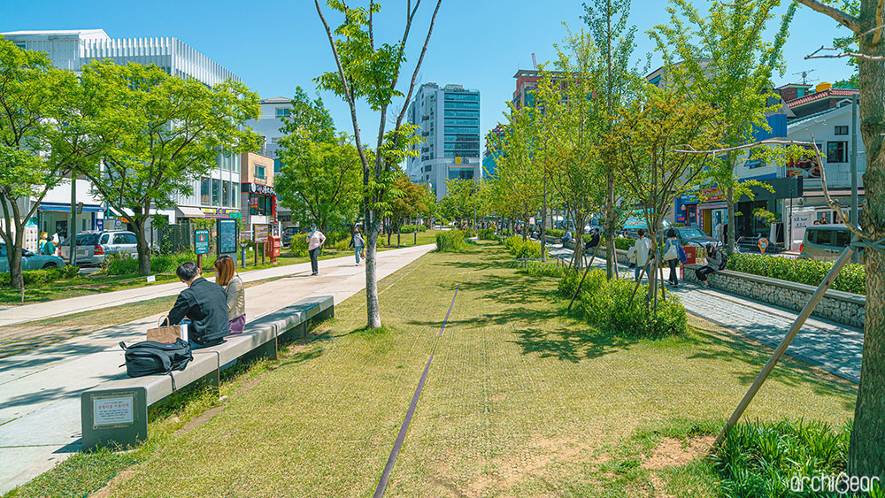 경의선 숲길의 녹지공간 일부. 왼편에는 산책중인 시민들이 휴식을 취할수 있도록 벤치가 설치되어있고, 남녀 한쌍이 앉아있다.