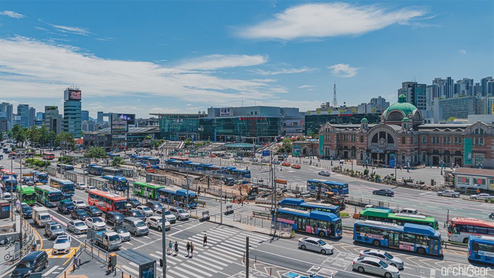 서울역 전경. 넓은 도로 위 버스와 자동차 뒤쪽으로, 오른편에는 옛날 서울역으로 사용된 문화역서울 건물이, 왼편에는 새롭게 지어진 서울역이 보인다